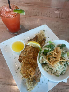 Crab stuffed flounder served with rice, a salad, lemon butter, and a cocktail at Grumble’s Seafood Co.