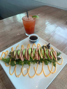 Seared tuna bowl topped with avocado and a refreshing cocktail at Grumble's Seafood Co.